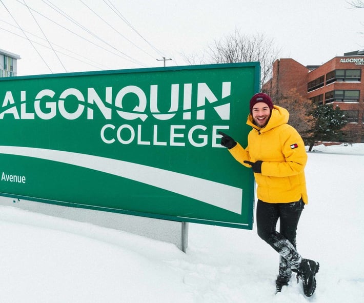 Ein Teilnehmer des AIFS Studieren im Auslands Programms steht vor dem Schild des Algonquin College in Ottawa, Kanada.